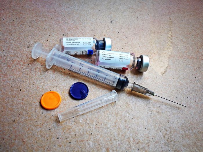High angle view of syringe with bottles on table