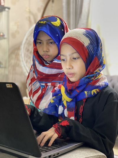 Online learning has become a new norm nowadays and a potrait shows two girls are   looking at laptop