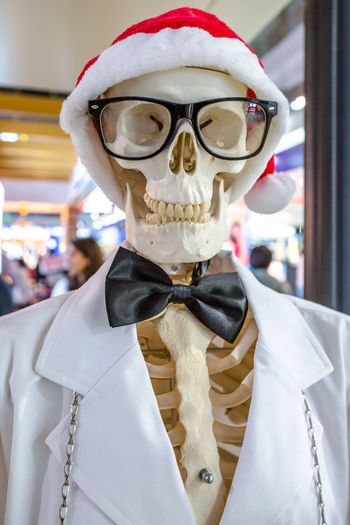 Close-up of human skeleton wearing santa hat outside shop