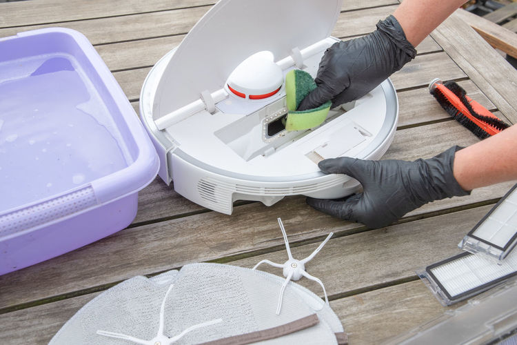 Woman washing a trash can in a robot vacuum cleaner, planned maintenance