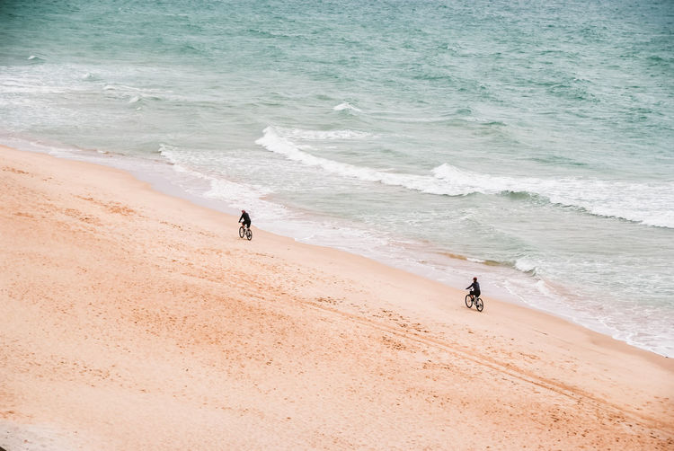 High angle view of people riding bicycle on beach