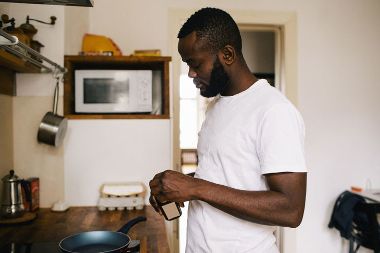 Side view of depressed man cooking in kitchen at home