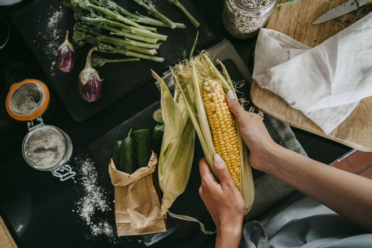 Directly above view of female chef peeling fresh corn at studio kitchen