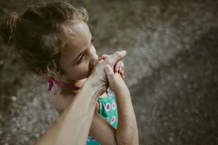 Cropped image of woman holding daughter's hand while standing on footpath