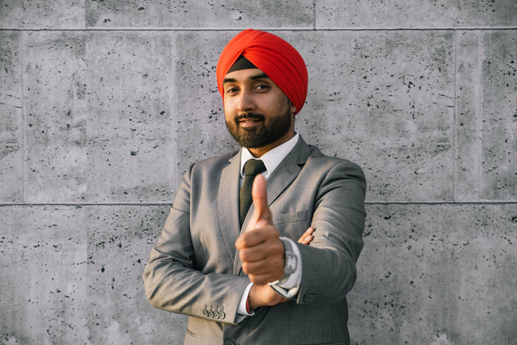 Portrait of smiling businessman wearing turban against wall