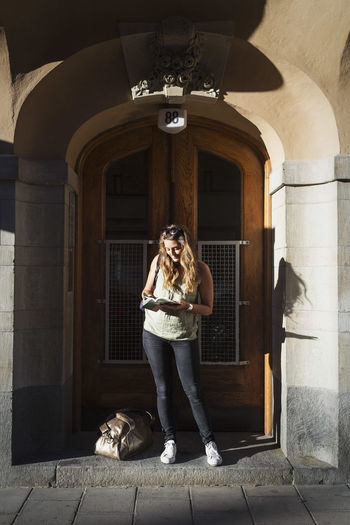 Female tourist reading guidebook while standing at doorway