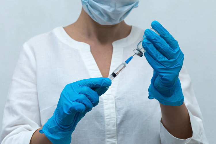 Midsection of doctor holding syringe with vial at hospital