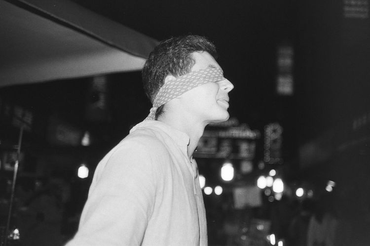 Side view of young man with blindfold standing outdoors