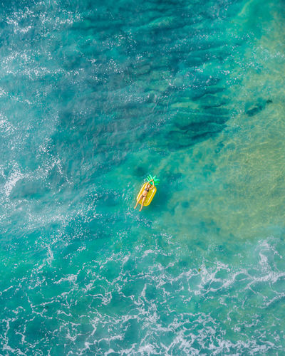 Drone view of woman relaxing on raft in sea