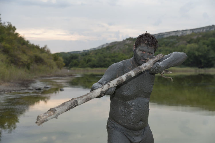 Portrait of man with mud on body against sky