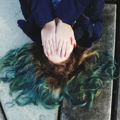 High angle view of shy woman covering face with hands while lying on floorboard