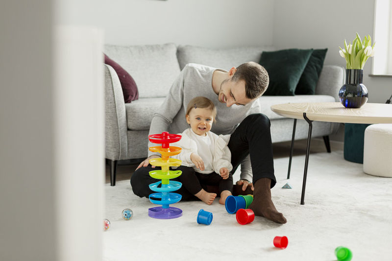 Father with toddler girl playing in living room