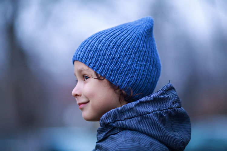 Close-up of smiling boy looking away during winter