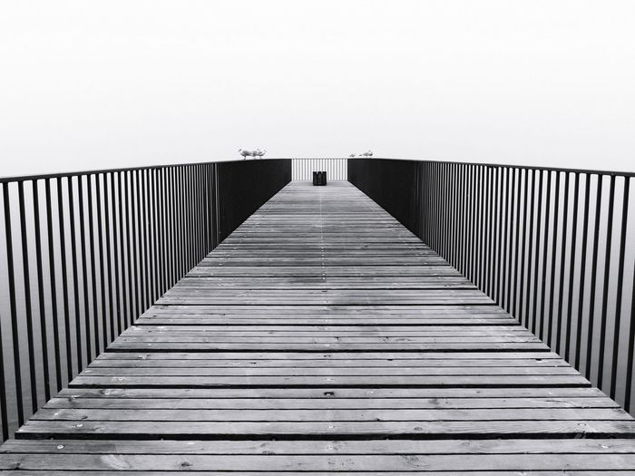 Wooden footbridge on pier against fogy sky