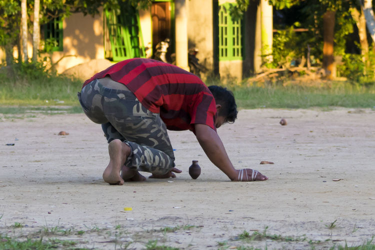 Man bending over spinning top on ground