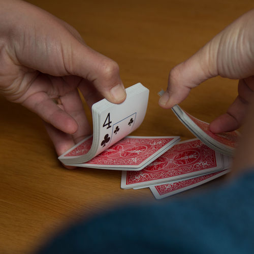Cropped image of person shuffling cards on table