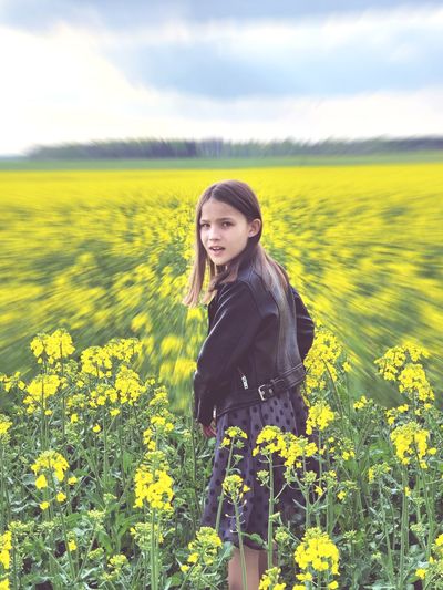 Young woman standing on yellow flower field