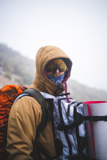 Hiker standing with sunglasses looking at camera during foggy day