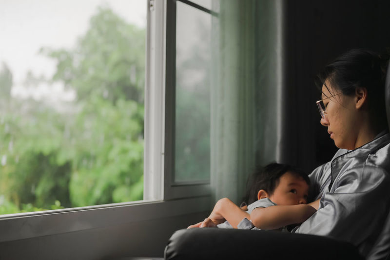 Mother and daughter against window