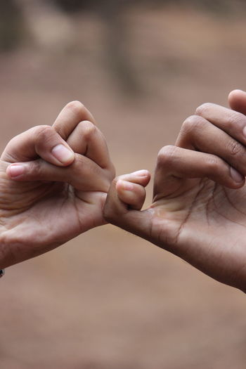 Close-up of man and woman giving pinkie promise