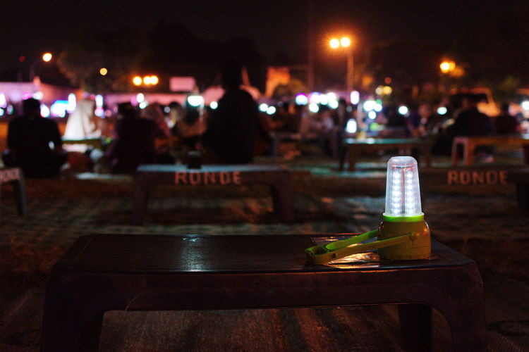 Close-up of wine bottles on table in city at night