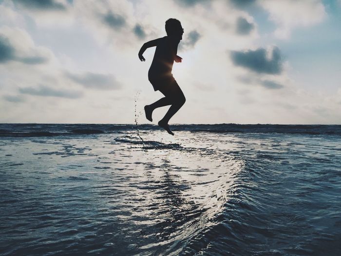 Silhouette of woman jumping in sea