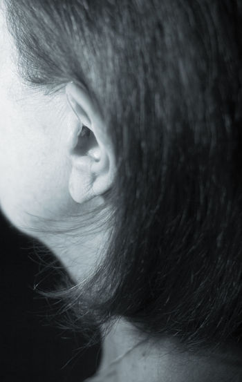 Close-up of woman with hearing aid against black background