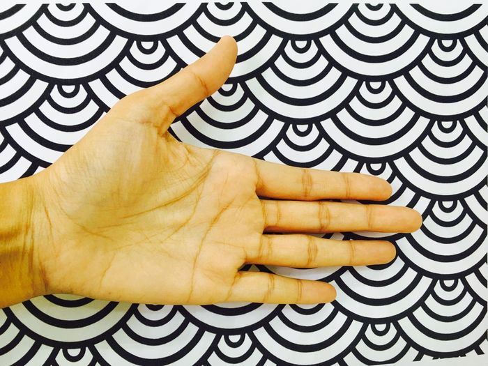 Cropped hand of person against patterned wall