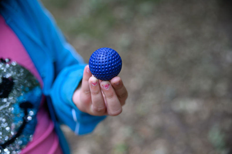 Midsection of girl holding blue ball