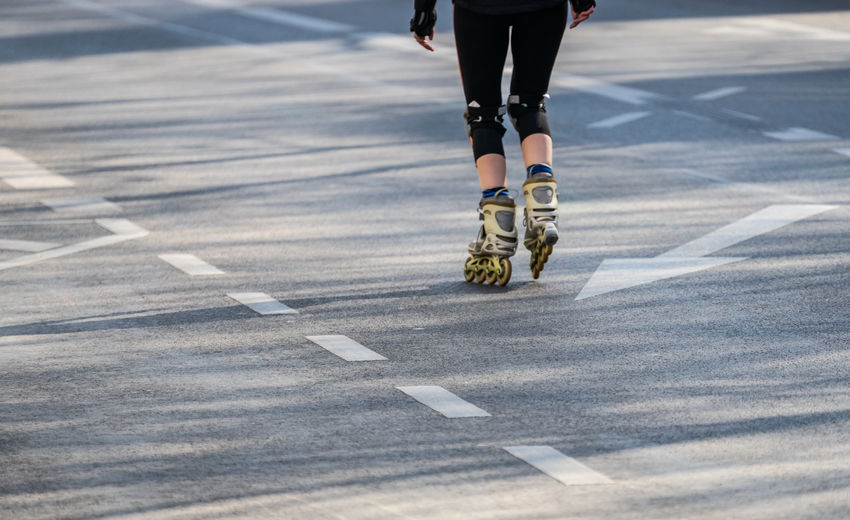 Low section of athlete skating on road in city
