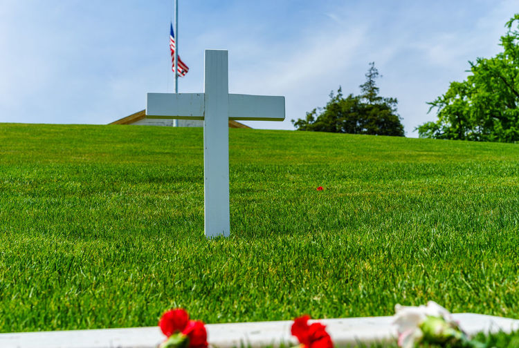 Wooden crucifix on lawn with american flag in background