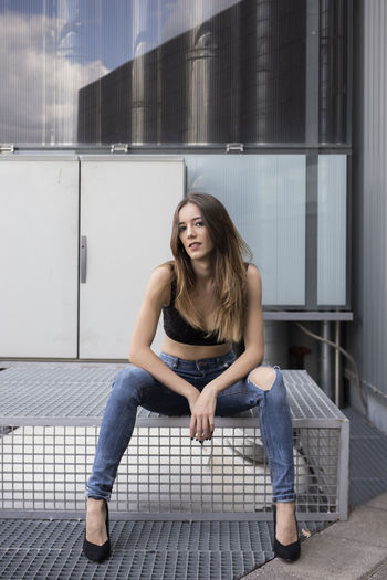 Woman sitting with fashion pose on industrial site
