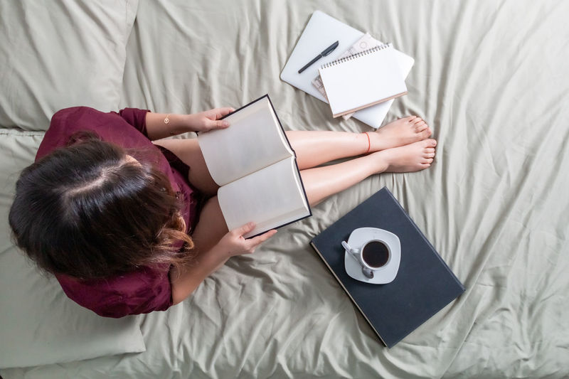 High angle view of woman using mobile phone on bed at home