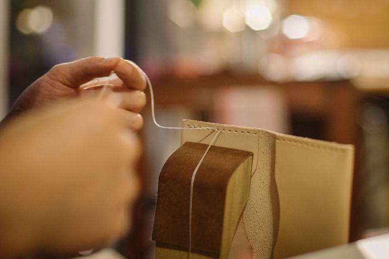 Close-up of human hand stitching leather
