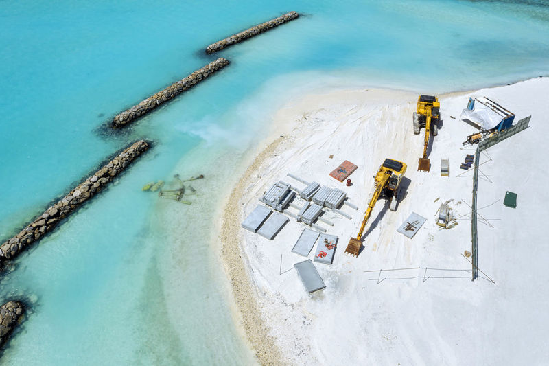 Maldives, aerial view of construction site at edge of sandy beach