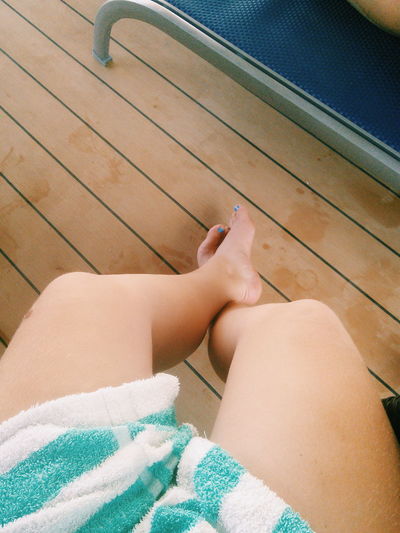 Low section of woman sitting on floorboard at poolside