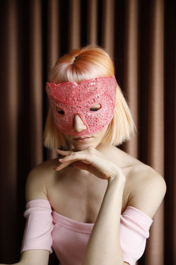 Portrait of woman covering face with pink hair