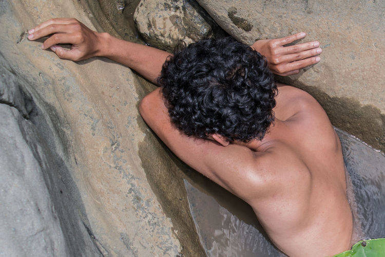 High angle view of man relaxing on rock