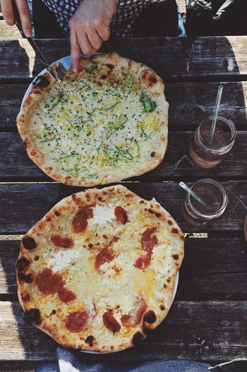 Close-up of hand holding pizza on table