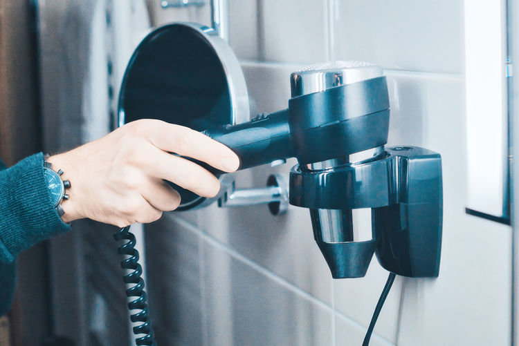 Midsection of woman holding hair dryer in bathroom