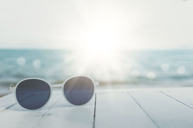 Close-up of sunglasses on sea against sky