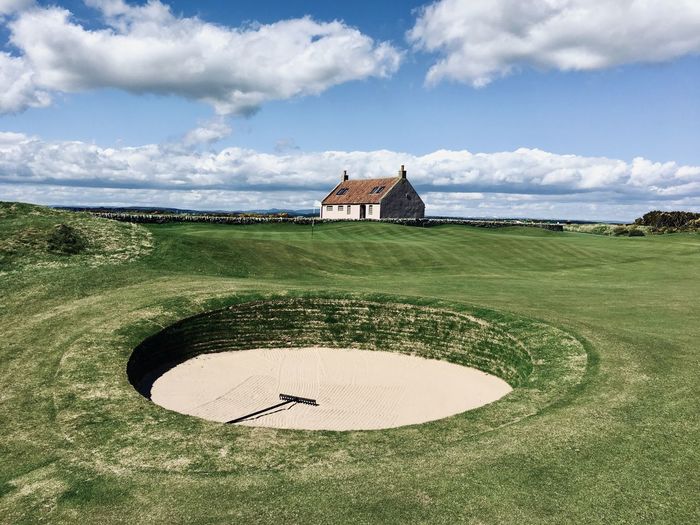 Golf bunker by building against sky