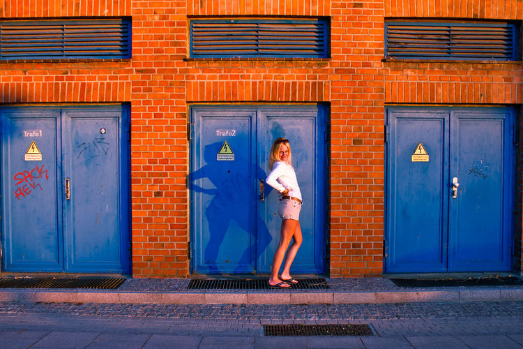 Woman standing against blue door