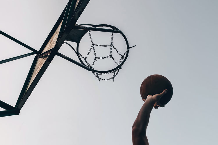 Silhouette of the hand of a basketball player throwing the ball into the ring.