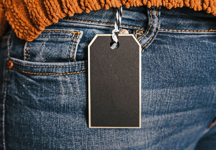 Midsection of woman wearing jeans with price tag