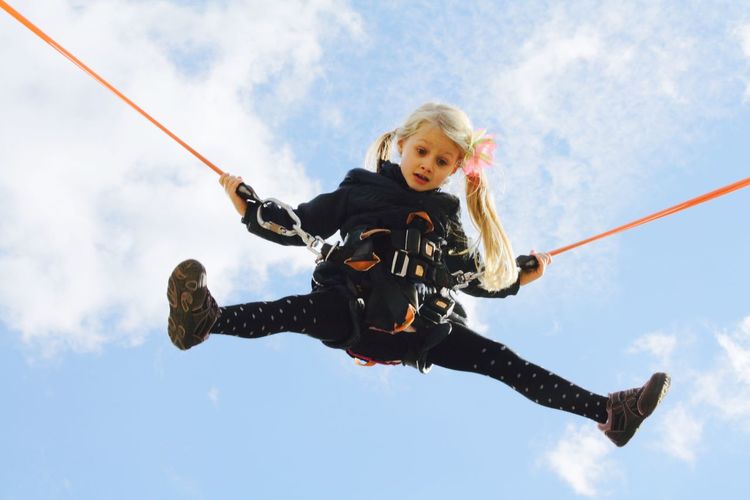 Low angle of girl hanging against sky