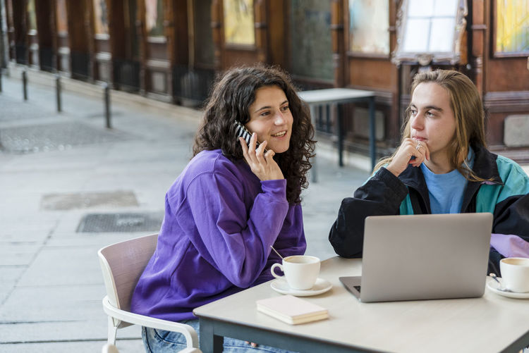 Young woman using mobile phone while sitting in cafe