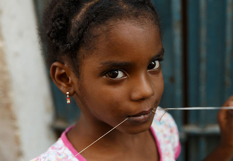 Close-up portrait of girl with thread in mouth