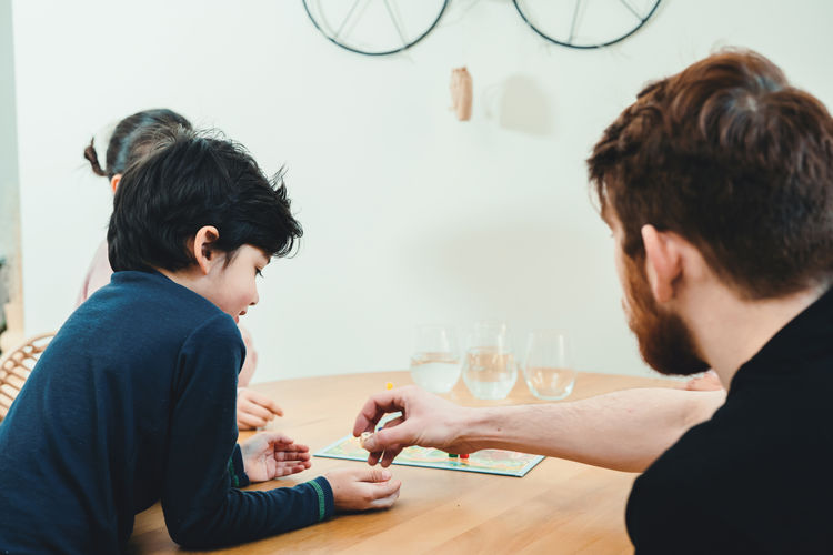 Rear view of father and son playing on table