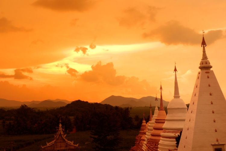 Panoramic view of temple and building against sky during sunset